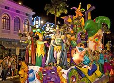 a float with people dressed in colorful costumes and masks on it's side at night