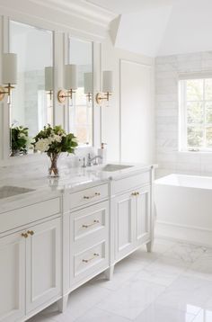 a white bathroom with marble counter tops and double sinks