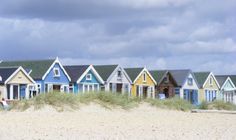 a row of colorful beach huts sitting on top of a sandy beach