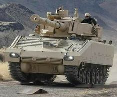 an army tank driving down a dirt road