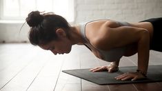 a woman doing push ups on a yoga mat