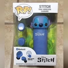 a blue stitch toy in its packaging on the floor with an earbud plugged into it