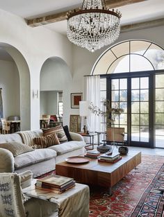 a living room filled with lots of furniture and a chandelier hanging from the ceiling