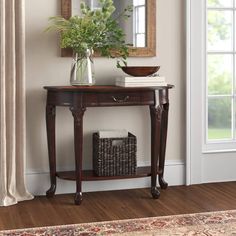 a wooden table with a mirror on top of it next to a basket and vase