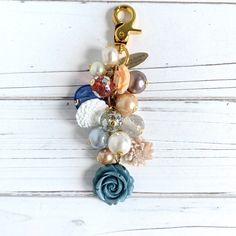 a close up of a key chain on a white wooden surface with beads and charms