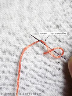 the needle is being used to sew an orange thread