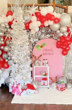 a room filled with lots of balloons and christmas decorations on top of a wooden floor