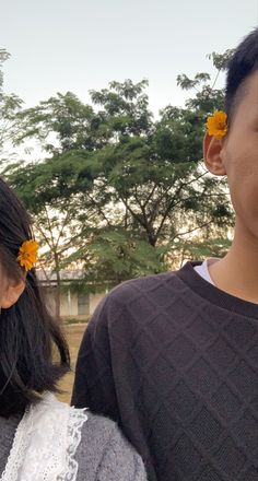 two people standing next to each other and one has a flower in her hair while the other holds a cell phone