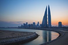 the sun is setting in front of some very tall buildings by the water's edge