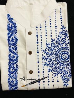 a white shirt with blue designs on it and a pair of scissors next to it