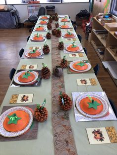 a long table with place settings and pine cones on the top, decorated for thanksgiving