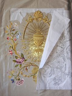 two white napkins with gold foil work on them, one is folded and the other has flowers