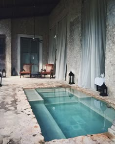 an indoor swimming pool in the middle of a room with chairs and tables around it