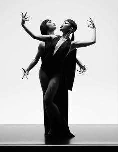 two women dressed in black and white pose for a fashion photo shoot with one holding the other's hand