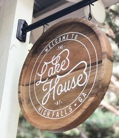 a wooden sign hanging from the side of a white and black building that says lake house at high falls bar