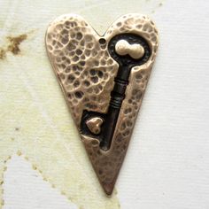 a heart shaped pendant with a key in it