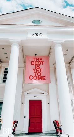 a pink sign that says the best is yet to come hanging on a white building