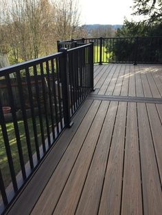 a wooden deck with black railings and trees in the background