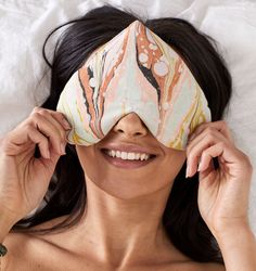 a woman laying on top of a bed wearing a sleep mask