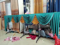 a room filled with lots of different colored curtains next to a bed covered in pink and blue sheets