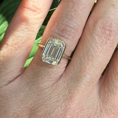 a woman's hand with a ring on it and an emerald stone in the middle