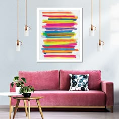 a living room with a pink couch and colorful art hanging on the wall above it