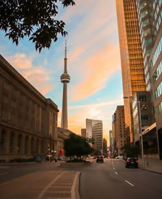 a city street with tall buildings and cars driving down the road at sunset or dawn