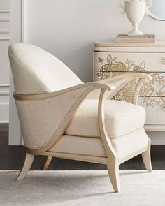 a white chair sitting in front of a mirror on top of a dresser next to a lamp