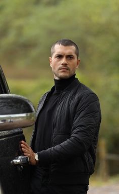 a man standing next to a car holding the door handle on it's side