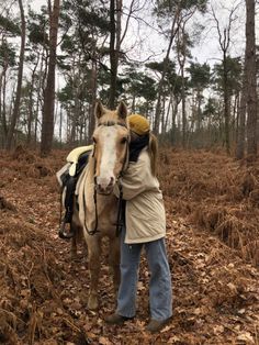 a person is standing next to a horse in the middle of some leaves and trees