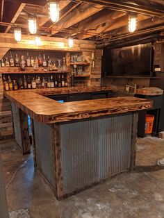 a bar made out of metal and wood with bottles on the top shelf, in a basement