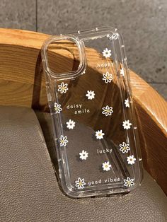 a clear case with white flowers on it sitting on a leather chair next to a wooden arm