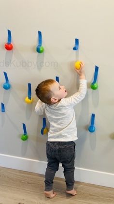 a little boy standing in front of a wall with magnets on it's side