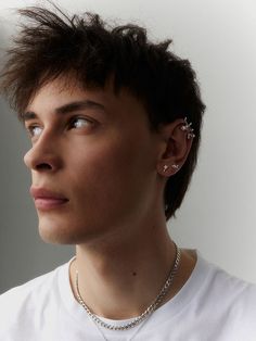 a young man with short hair and piercings on his ear wearing a white t - shirt