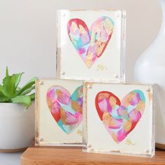 two hearts are painted on white canvases next to a potted succulent