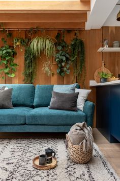 a blue couch sitting on top of a rug in a living room next to a wooden wall