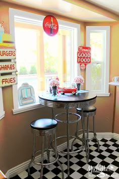 a kitchen with black and white checkered flooring, two stools at the bar