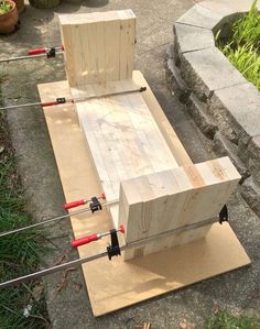 a wooden bench sitting on top of a piece of plywood next to some grass