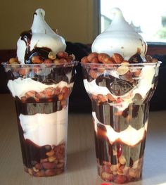 two glasses filled with dessert sitting on top of a table