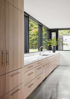 a kitchen with large windows and wooden cabinets