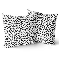 two pillows with black and white spots on them, one in the shape of an animal print