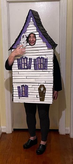 a woman standing in front of a cardboard house