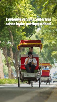 a man driving a red cart down a street with trees in the backgroud