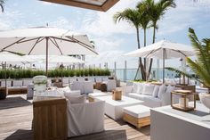 an outdoor seating area with umbrellas and chairs on the deck overlooking the ocean in miami