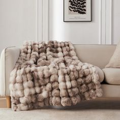 a couch with a blanket on top of it in front of a white wall and floor