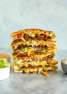 a stack of quesadillas sitting on top of a counter next to a bowl of salsa