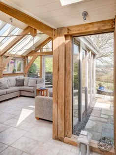 a living room filled with lots of furniture under a skylight covered in glass and wood