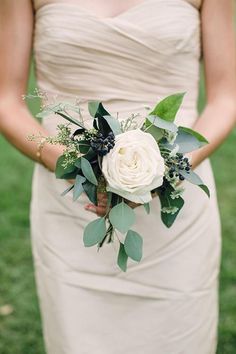 the bride is holding her wedding bouquet in her hand and she is wearing a white dress