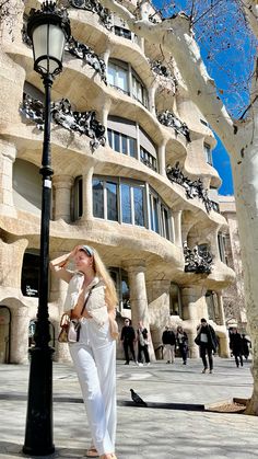 a woman standing next to a lamp post near a building that looks like a tree