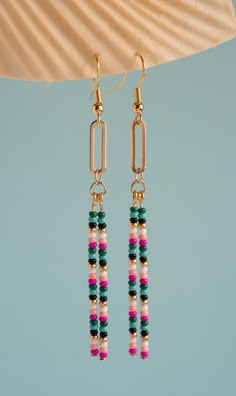 two pairs of earrings hanging from the side of a lamp shade with pink, green and white beads